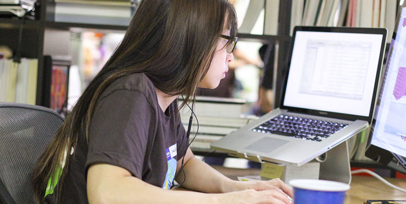 Woman at the computer publishing software with a mac book pro.