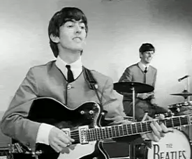 George Harrison playing on his guitar